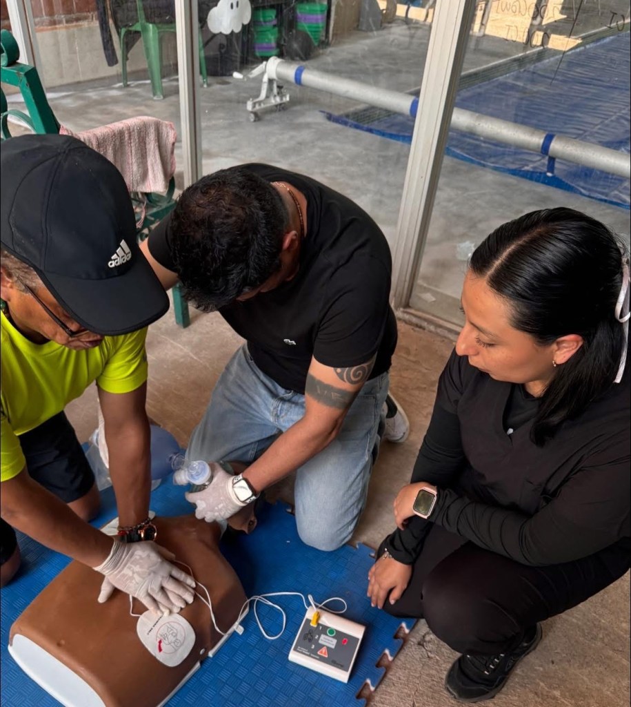 Participantes practican RCP con un maniquí adulto y un DAE de entrenamiento.